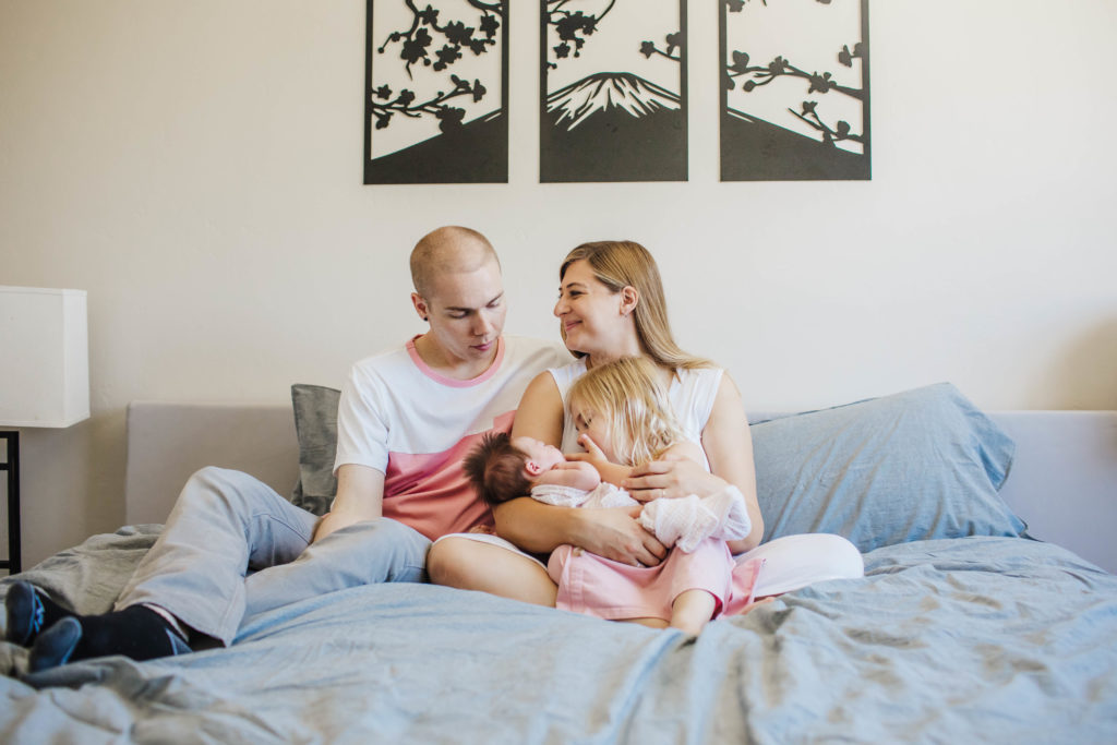 Image depicting family snuggled on bed during newborn session