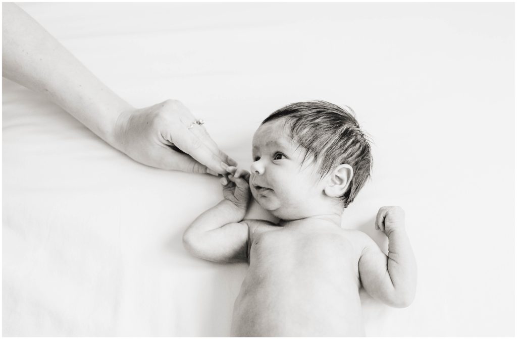 Image of baby holding mom's hand depicting lifestyle newborn photography