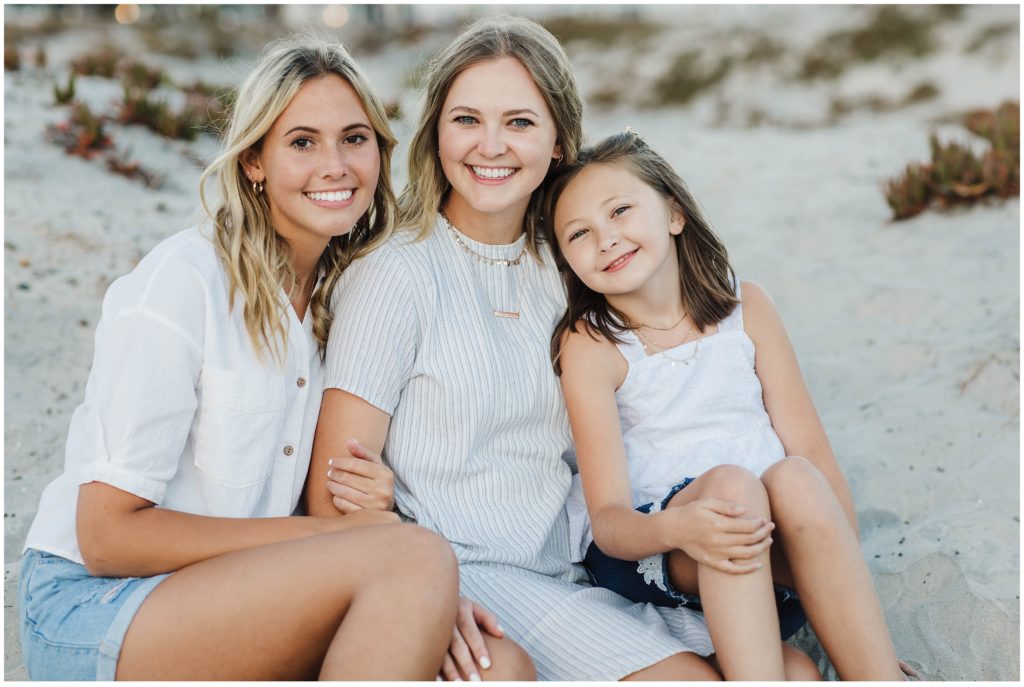 Sisters sitting on the beach during a family photoshoot in San Diego