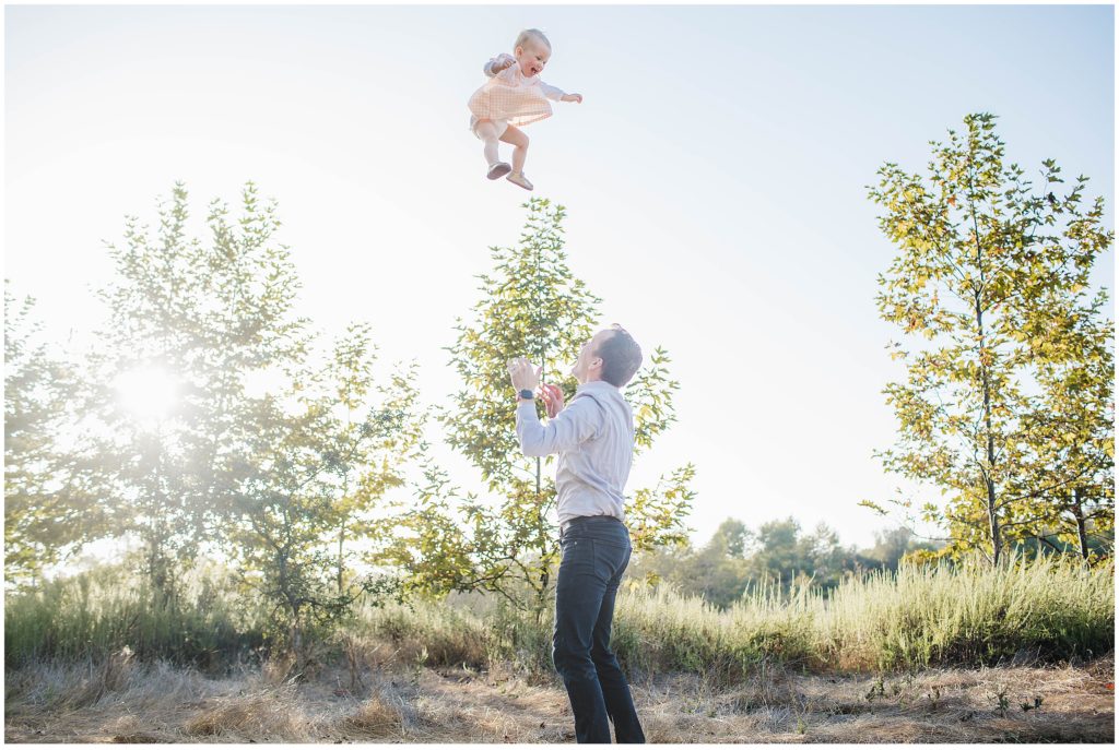Image of dad throwing daughter in the air while taking photos at Penasquitos Ranch house